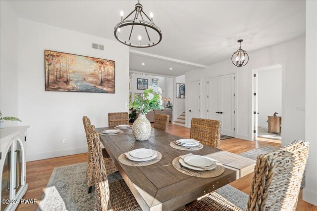 dining space with light wood-type flooring and an inviting chandelier