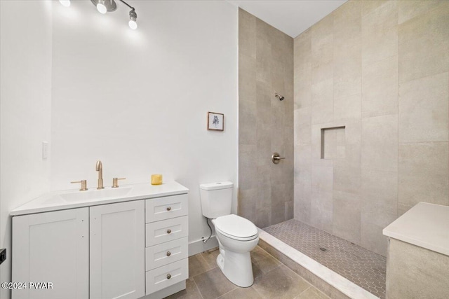 bathroom featuring a tile shower, vanity, and toilet