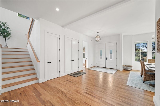 foyer entrance featuring a chandelier, beam ceiling, and light hardwood / wood-style floors