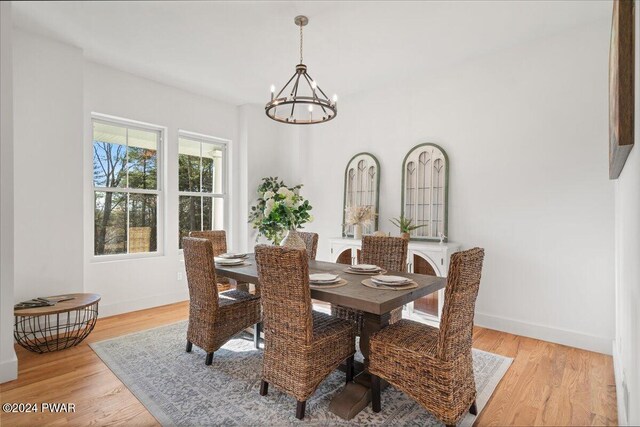 dining room with light wood-type flooring and a notable chandelier