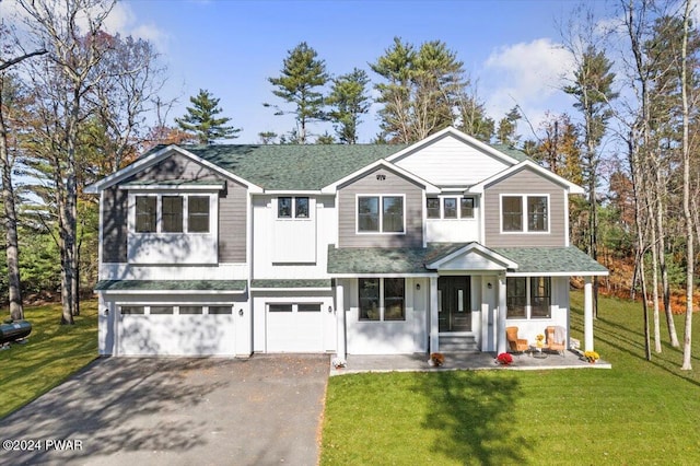 view of front of home with covered porch, a garage, and a front yard