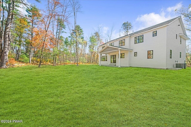 back of house with central air condition unit and a lawn