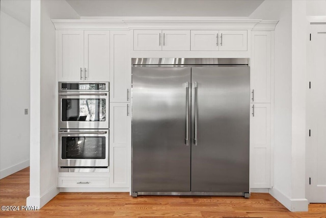 kitchen with white cabinetry, stainless steel appliances, and light hardwood / wood-style floors