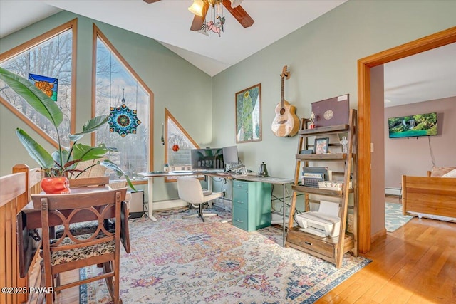 office area with ceiling fan, a baseboard heating unit, vaulted ceiling, and light hardwood / wood-style flooring