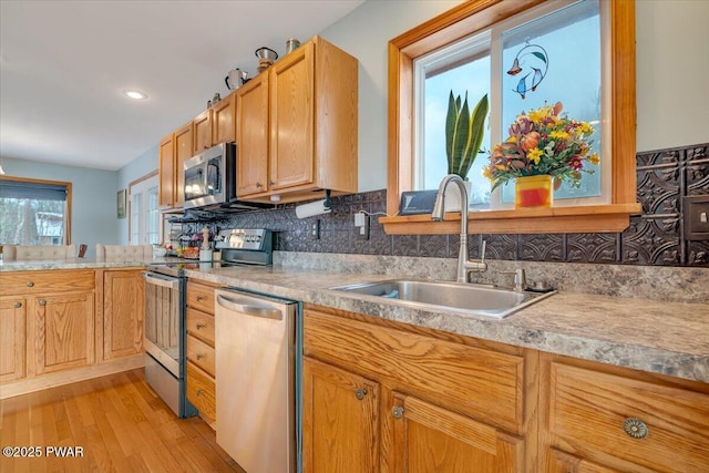 kitchen featuring decorative backsplash, sink, stainless steel appliances, and light hardwood / wood-style floors