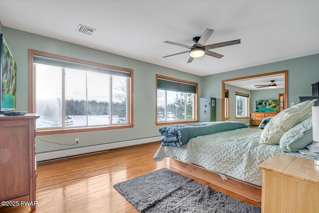 bedroom featuring baseboard heating, ceiling fan, and light hardwood / wood-style flooring