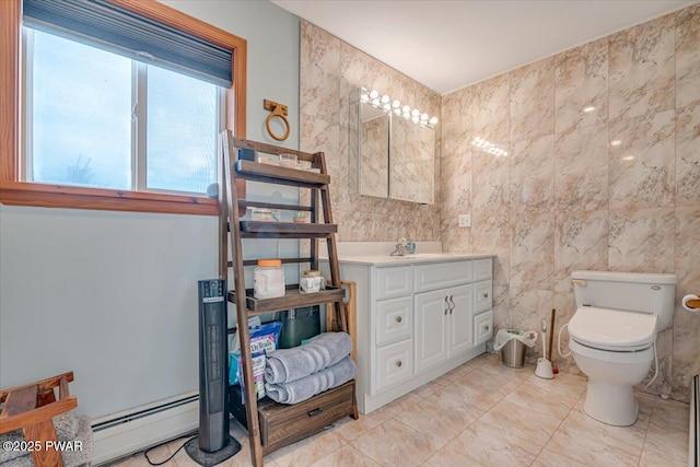 bathroom with toilet, vanity, baseboard heating, and tile walls