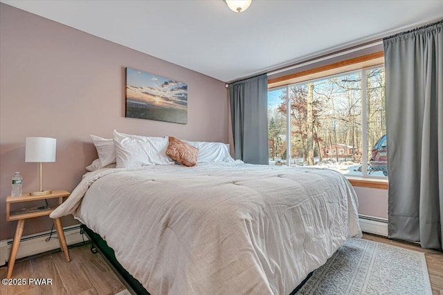 bedroom featuring wood-type flooring and a baseboard heating unit