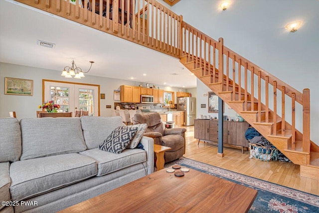 living room featuring french doors, a chandelier, and light wood-type flooring