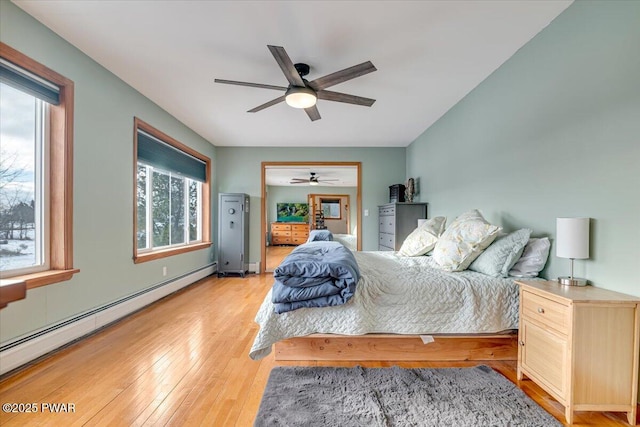 bedroom featuring light hardwood / wood-style floors, baseboard heating, and ceiling fan