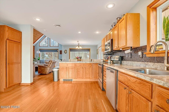 kitchen featuring appliances with stainless steel finishes, tasteful backsplash, sink, light hardwood / wood-style flooring, and a chandelier