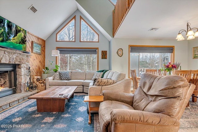 living room with wooden walls, a fireplace, lofted ceiling, and an inviting chandelier