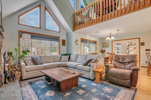 living room featuring an inviting chandelier, high vaulted ceiling, a baseboard radiator, and hardwood / wood-style flooring