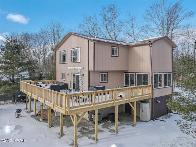 snow covered back of property featuring cooling unit and a wooden deck