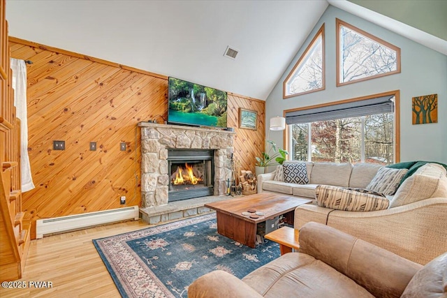 living room with a fireplace, a baseboard radiator, and wooden walls