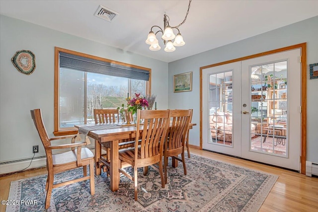 dining area featuring french doors, light hardwood / wood-style floors, and a notable chandelier