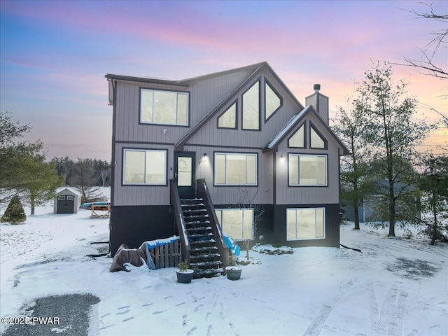 snow covered rear of property with a storage shed