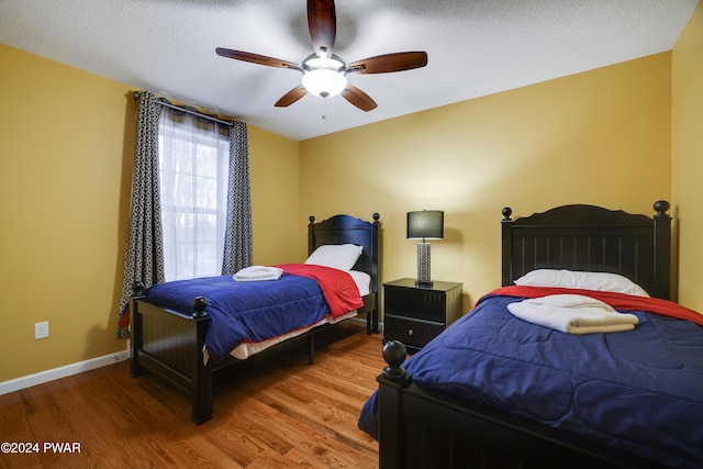 bedroom with ceiling fan, wood-type flooring, and a textured ceiling