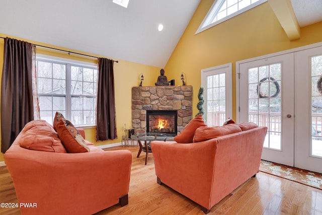 living room with a fireplace, french doors, light wood-type flooring, and a healthy amount of sunlight