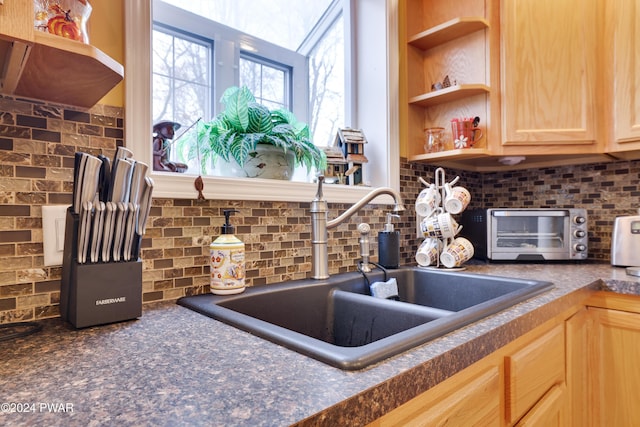 kitchen featuring light brown cabinetry, tasteful backsplash, and sink