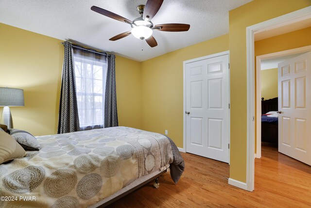 bedroom featuring ceiling fan, light hardwood / wood-style floors, and a textured ceiling