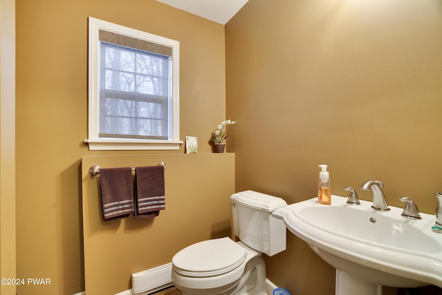 bathroom featuring toilet, a baseboard heating unit, and sink