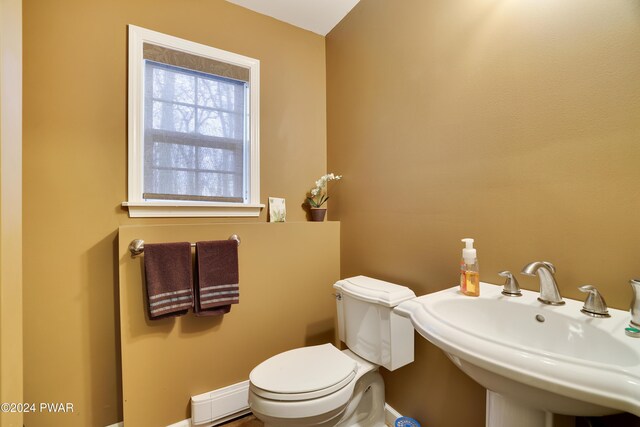 bathroom featuring toilet, a baseboard heating unit, and sink