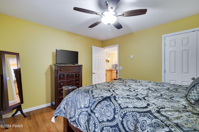 bedroom featuring hardwood / wood-style floors, ceiling fan, a textured ceiling, and a closet