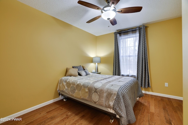 bedroom with a textured ceiling, hardwood / wood-style flooring, and ceiling fan