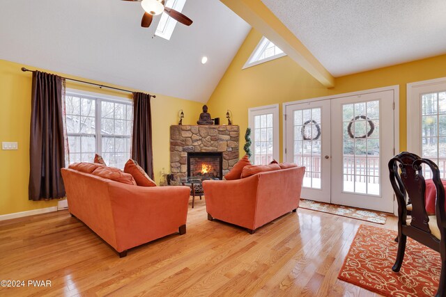 living room with a fireplace, ceiling fan, french doors, and light wood-type flooring