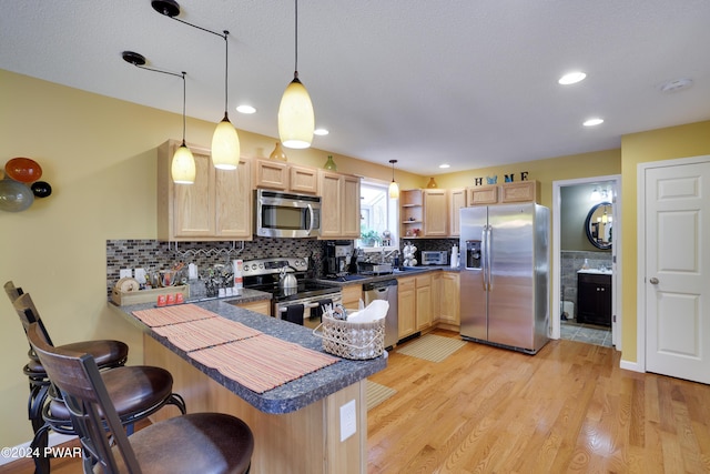 kitchen with pendant lighting, kitchen peninsula, stainless steel appliances, and light brown cabinetry