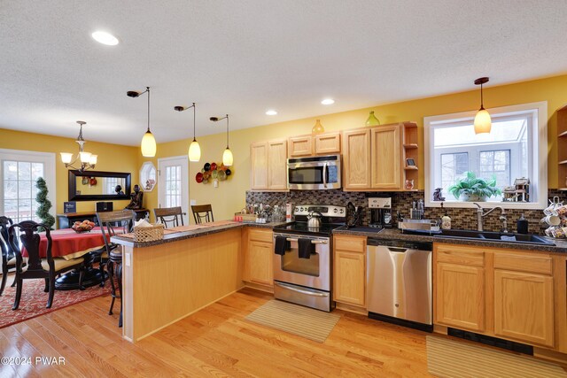 kitchen featuring pendant lighting, an inviting chandelier, sink, appliances with stainless steel finishes, and kitchen peninsula