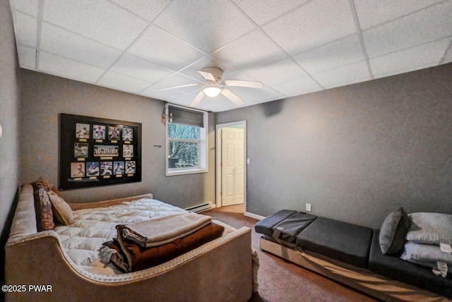 bedroom with baseboards, a drop ceiling, a baseboard radiator, ceiling fan, and carpet