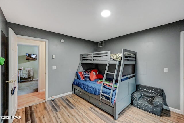 bedroom featuring baseboards, visible vents, and wood finished floors