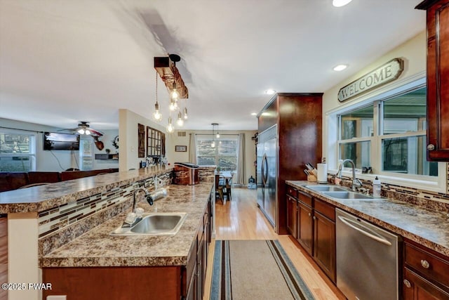 kitchen featuring stainless steel appliances, a sink, a center island with sink, and tasteful backsplash