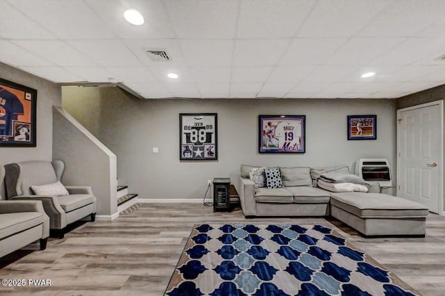 living room featuring visible vents, stairway, wood finished floors, a drop ceiling, and baseboards