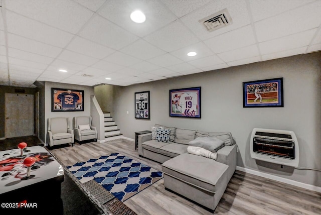 living area featuring heating unit, stairway, visible vents, and wood finished floors