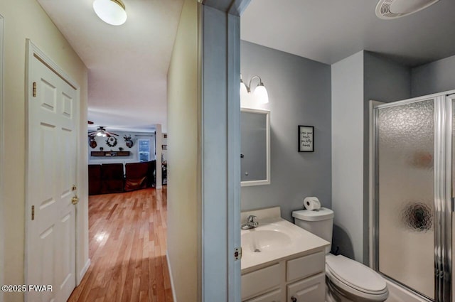 full bath featuring vanity, wood finished floors, a shower stall, and toilet