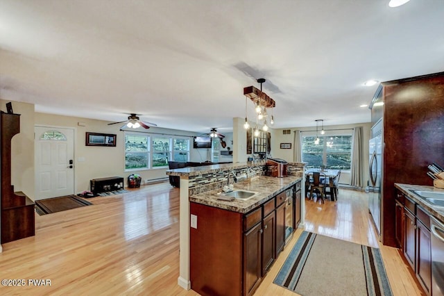 kitchen featuring light wood finished floors, hanging light fixtures, a sink, light stone countertops, and plenty of natural light