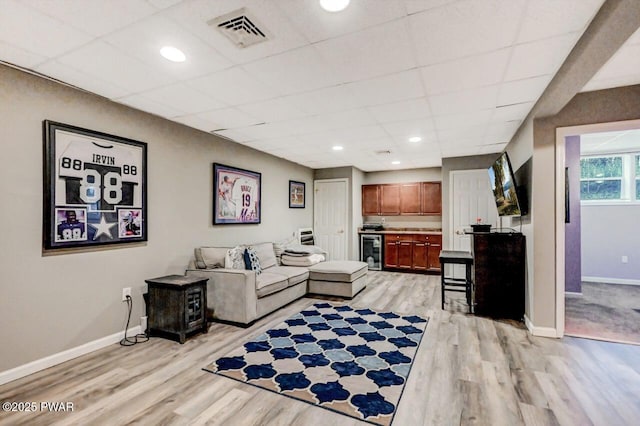 living room with light wood finished floors, beverage cooler, visible vents, baseboards, and a drop ceiling