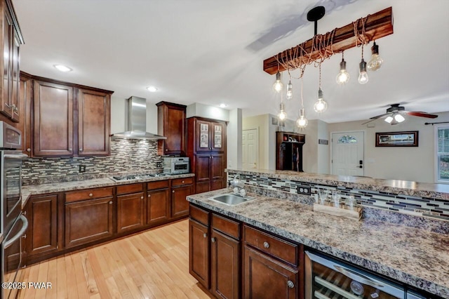 kitchen featuring a sink, wall chimney range hood, gas stovetop, and light stone countertops