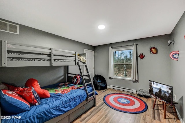 bedroom with baseboards, a baseboard radiator, visible vents, and wood finished floors