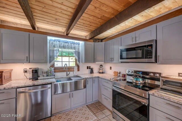 29 Tanglewood Ln, Lake Ariel, PA 18436 - kitchen with stainless steel appliances, a wooden ceiling with exposed beams, light tile patterned flooring, light stone counters, and gray cabinetry