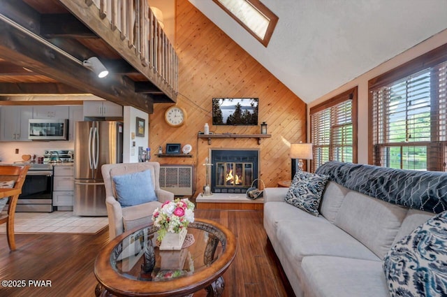 29 Tanglewood Ln, Lake Ariel, PA 18436 - living room featuring vaulted ceiling, light wood-style flooring, a glass covered fireplace, and wooden walls