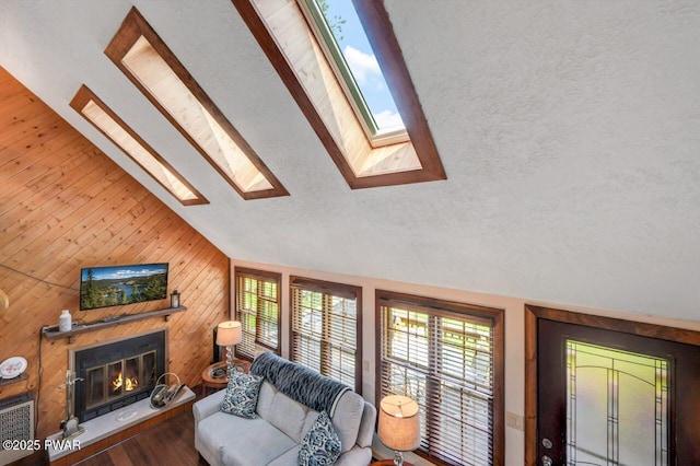 29 Tanglewood Ln, Lake Ariel, PA 18436 - living area with lofted ceiling, a glass covered fireplace, a skylight, a textured ceiling, and wooden walls
