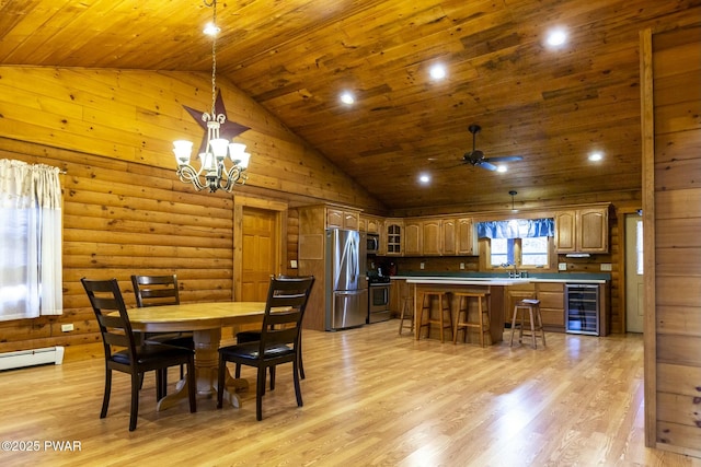 dining area with high vaulted ceiling, ceiling fan with notable chandelier, rustic walls, light hardwood / wood-style floors, and beverage cooler