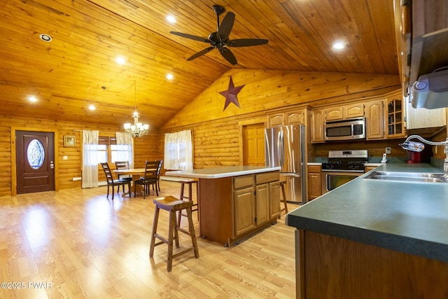 kitchen featuring a kitchen bar, appliances with stainless steel finishes, sink, log walls, and light hardwood / wood-style flooring