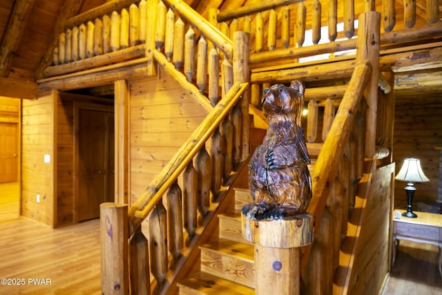 staircase featuring lofted ceiling with beams, log walls, wood-type flooring, and wooden ceiling