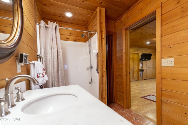 bathroom with a shower with curtain, wood walls, wooden ceiling, and vanity