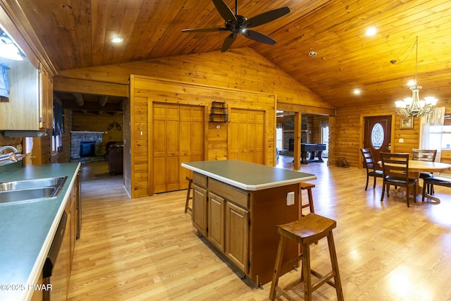 kitchen featuring light wood-type flooring, rustic walls, ceiling fan with notable chandelier, sink, and a center island